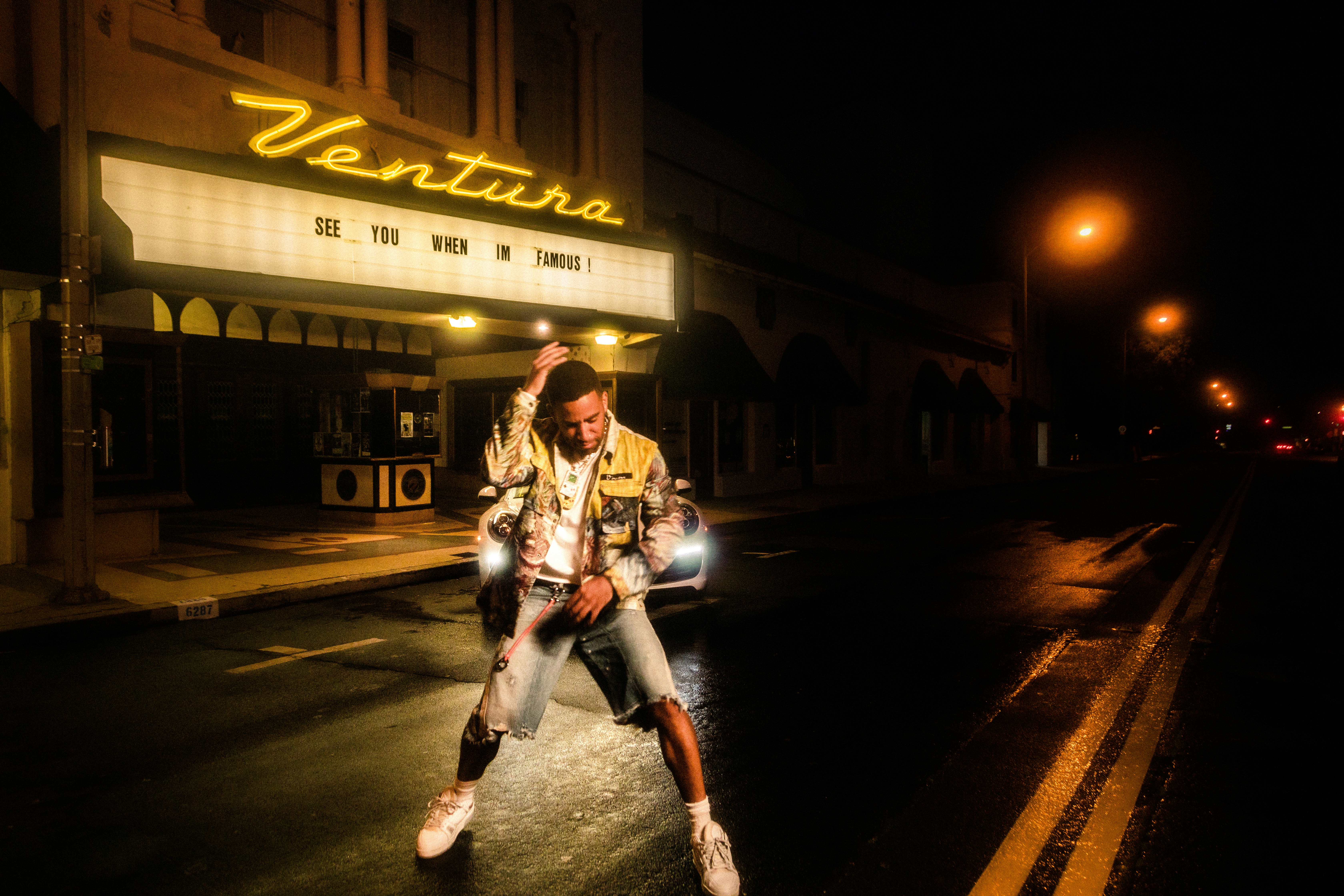 man in black and white jacket standing on road during night time